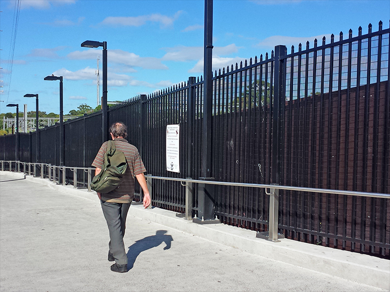 man walks past newly erected fencing at a train station