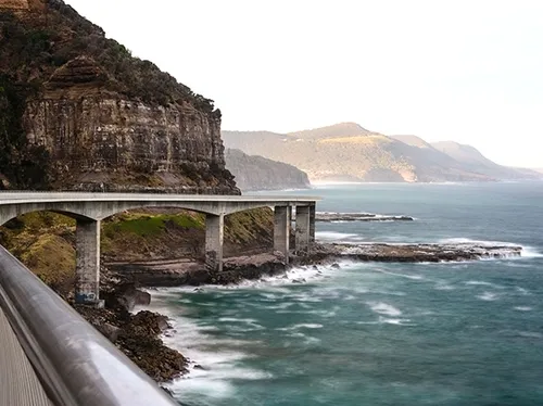 Our Commitment 3 a road that is elevated over a beautiful seaside landscape 1